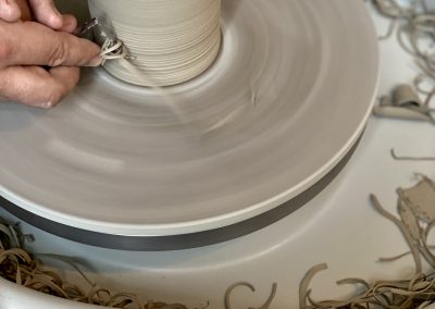 Eine Vase wird auf einer Drehscheibe getrimmt. sieht den Prozess mit den typischen Werkzeugen, die dafür verwendet werden.